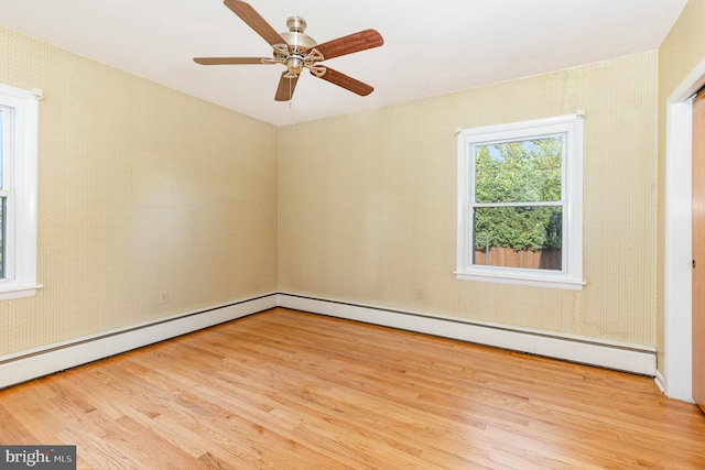 empty room with ceiling fan, light hardwood / wood-style floors, and a baseboard heating unit