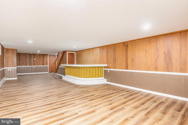 bar featuring light wood-type flooring and wooden walls