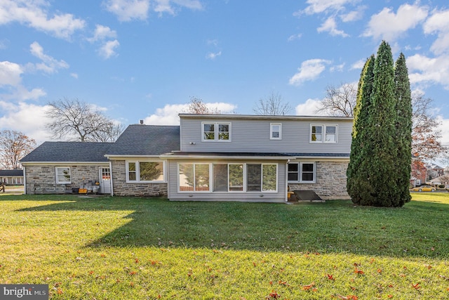 rear view of property featuring a lawn and a sunroom