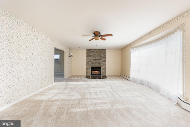 unfurnished living room with ceiling fan, a fireplace, light colored carpet, and a baseboard heating unit