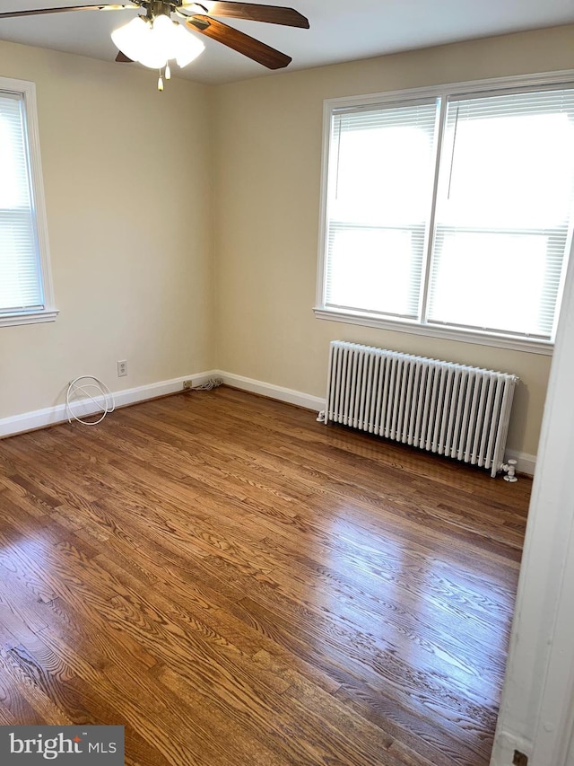 spare room featuring radiator, ceiling fan, and dark hardwood / wood-style flooring