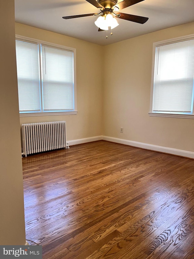 empty room featuring dark hardwood / wood-style floors, ceiling fan, and radiator