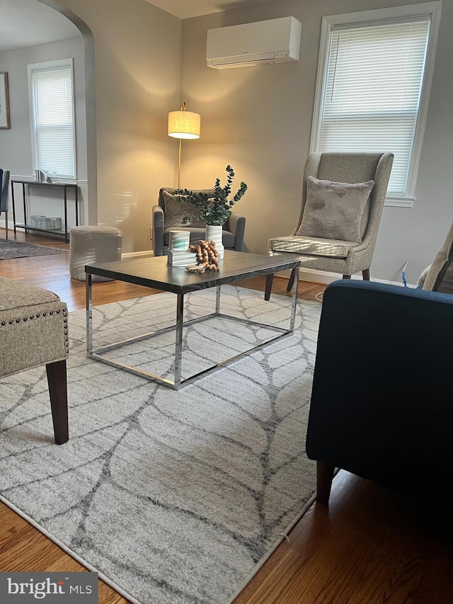 sitting room with wood-type flooring and a wall mounted air conditioner