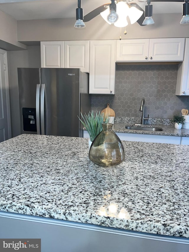 kitchen with white cabinetry, sink, backsplash, and stainless steel fridge