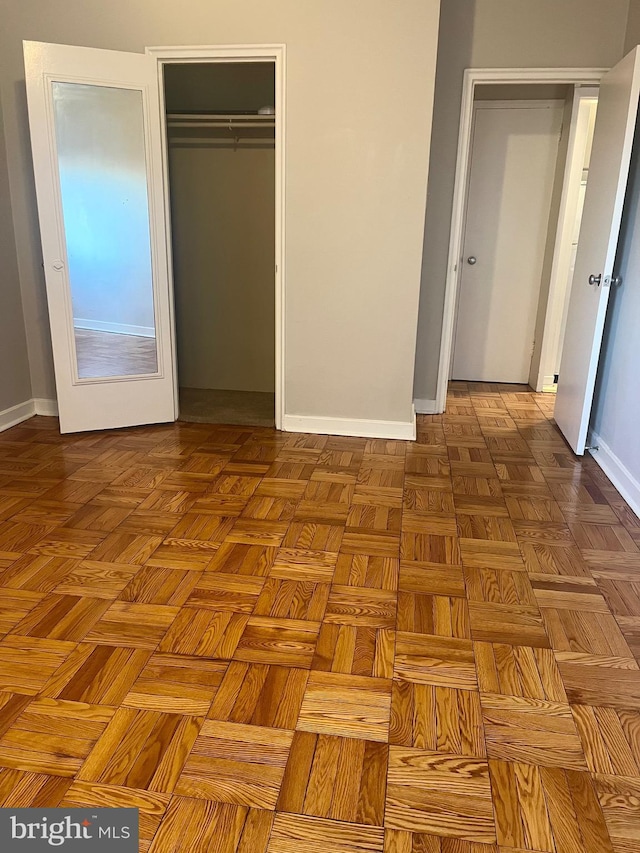 unfurnished bedroom featuring parquet floors and multiple closets