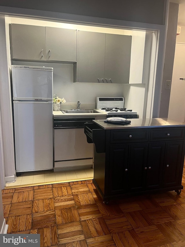 kitchen with dishwasher, stove, sink, stainless steel refrigerator, and light parquet flooring