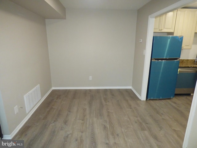 kitchen with stainless steel appliances, dark stone counters, and light wood-type flooring