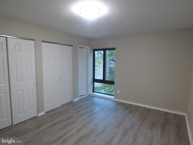 unfurnished bedroom with multiple closets and hardwood / wood-style flooring