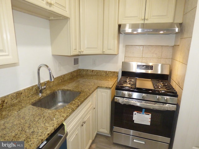 kitchen featuring stainless steel appliances, sink, backsplash, and light stone countertops