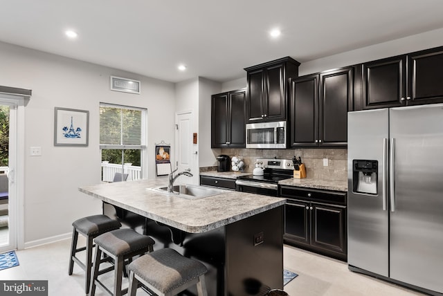 kitchen with sink, a kitchen island with sink, a healthy amount of sunlight, and stainless steel appliances