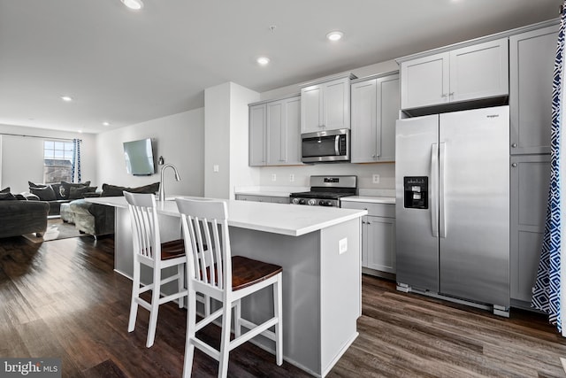 8510 Randell Ridge Rd, Frederick, MD 21704 - kitchen featuring appliances with stainless steel finishes, dark wood-style floors, an island with sink, light countertops, and a breakfast bar