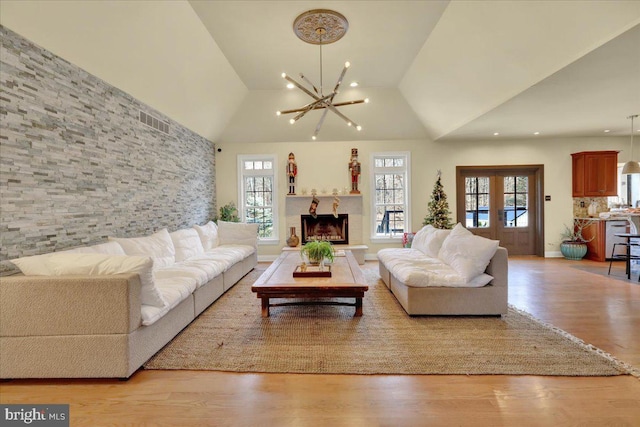 living room with plenty of natural light, a chandelier, light wood-style flooring, vaulted ceiling, and recessed lighting