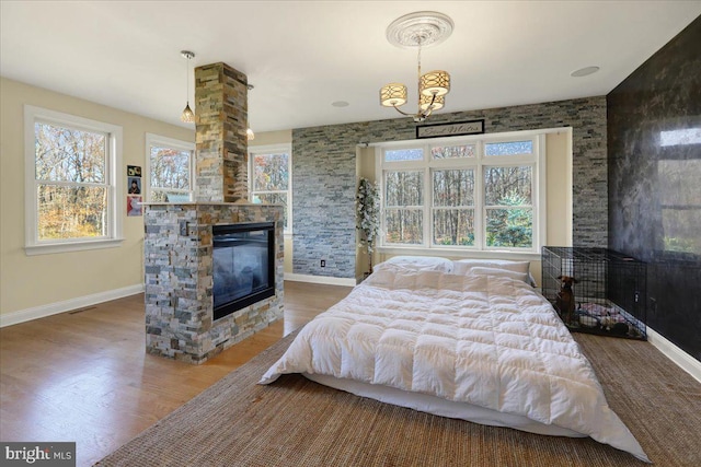 bedroom with a fireplace, hardwood / wood-style flooring, and a notable chandelier