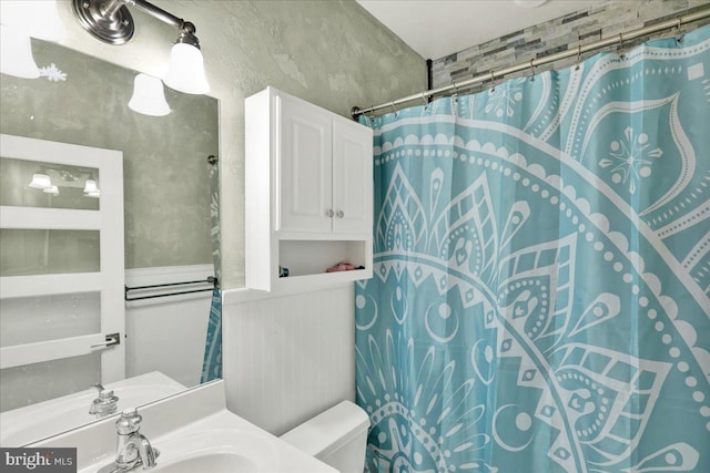 bathroom featuring sink, a shower with shower curtain, and toilet