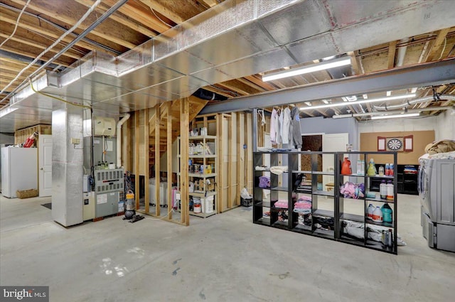 basement with white refrigerator, washing machine and dryer, and heating unit