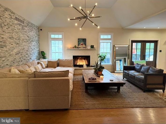 living room featuring wood-type flooring, vaulted ceiling, a healthy amount of sunlight, and a notable chandelier