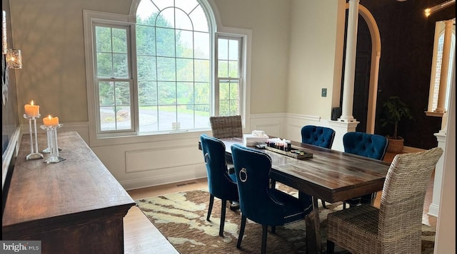 dining room with decorative columns, plenty of natural light, and hardwood / wood-style flooring