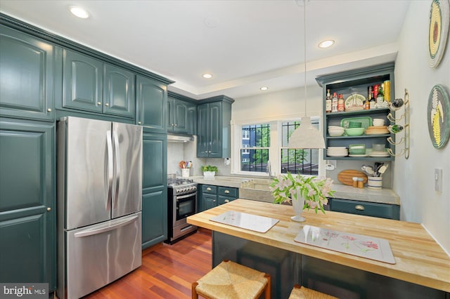 kitchen with butcher block counters, appliances with stainless steel finishes, hanging light fixtures, sink, and dark wood-type flooring