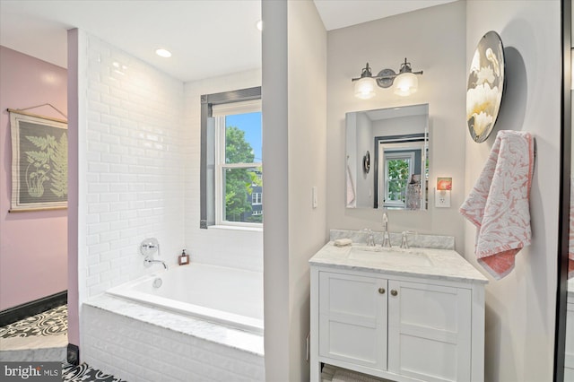 bathroom featuring a relaxing tiled tub and vanity