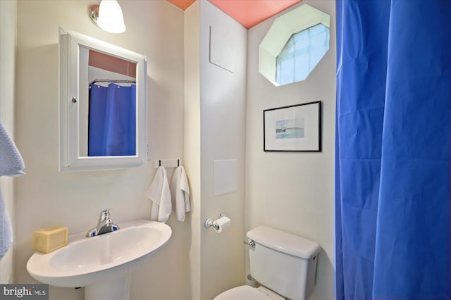 bathroom with toilet, a shower with curtain, and sink