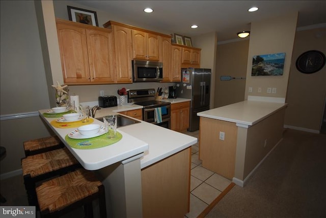 kitchen featuring sink, kitchen peninsula, appliances with stainless steel finishes, ornamental molding, and a breakfast bar area