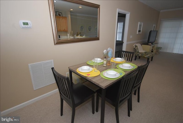 carpeted dining area with ornamental molding