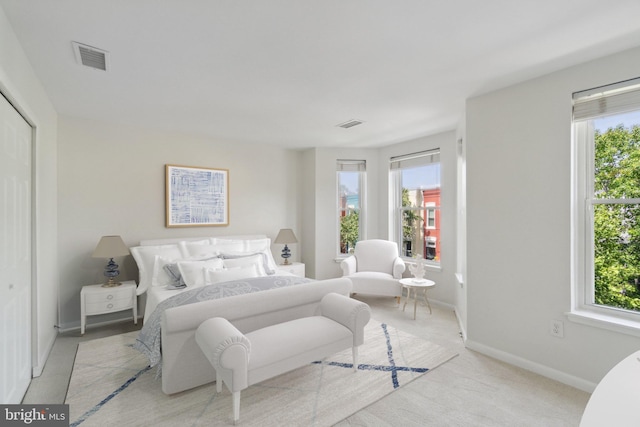 bedroom with light colored carpet and multiple windows