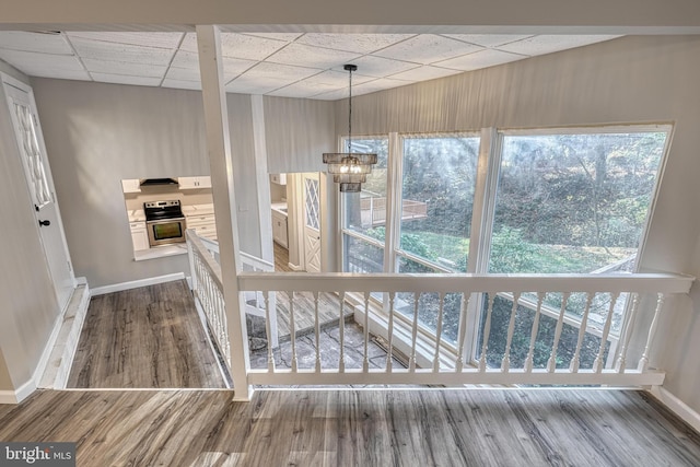 unfurnished dining area featuring a paneled ceiling, a chandelier, and hardwood / wood-style floors