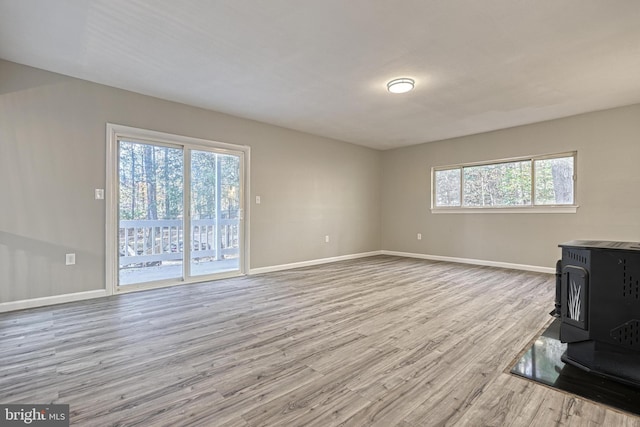 living room with a wood stove, light hardwood / wood-style floors, and plenty of natural light