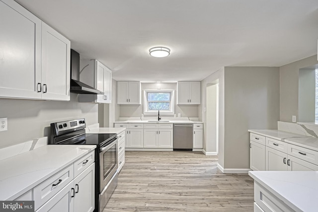 kitchen featuring white cabinets, light hardwood / wood-style floors, wall chimney range hood, and appliances with stainless steel finishes