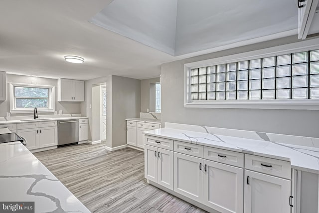 kitchen with light stone counters, light wood-type flooring, sink, white cabinets, and dishwasher