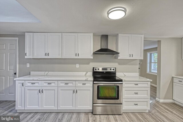 kitchen with wall chimney range hood, white cabinetry, stainless steel electric range oven, and light wood-type flooring