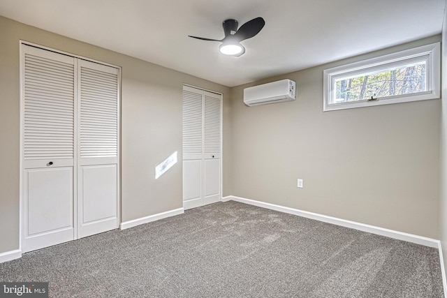 unfurnished bedroom with ceiling fan, a wall mounted AC, multiple closets, and carpet