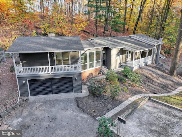 view of front facade with a garage, a sunroom, and covered porch