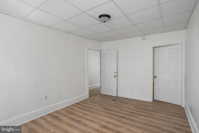 empty room with a paneled ceiling and wood-type flooring