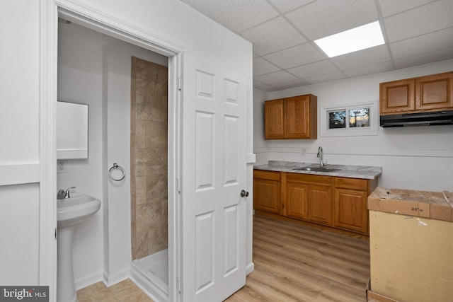 kitchen with a paneled ceiling, sink, and light hardwood / wood-style floors