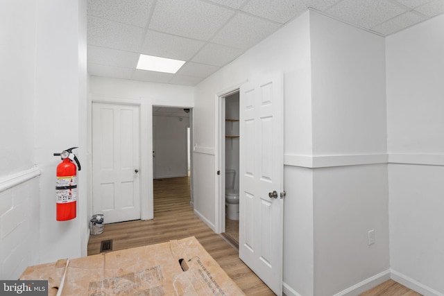 corridor with a paneled ceiling and light hardwood / wood-style flooring