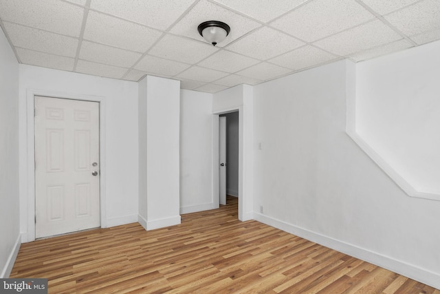 spare room featuring a paneled ceiling and light wood-type flooring