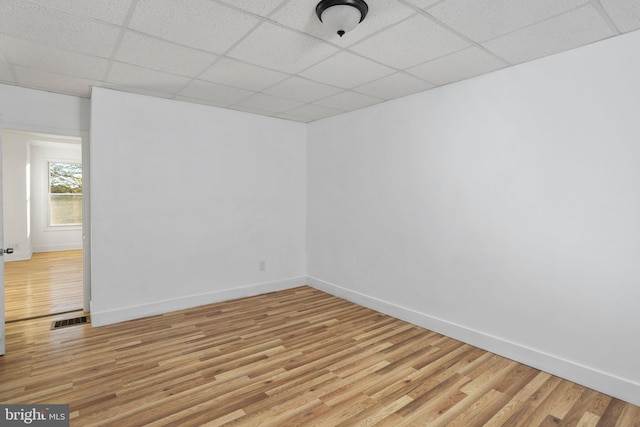 unfurnished room featuring light wood-type flooring and a paneled ceiling