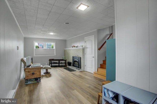 interior space featuring ornamental molding, a brick fireplace, and light hardwood / wood-style floors