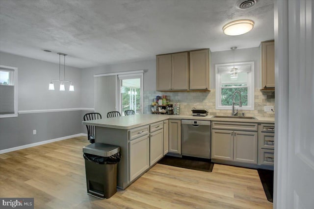 kitchen featuring sink, decorative light fixtures, light hardwood / wood-style flooring, dishwasher, and kitchen peninsula