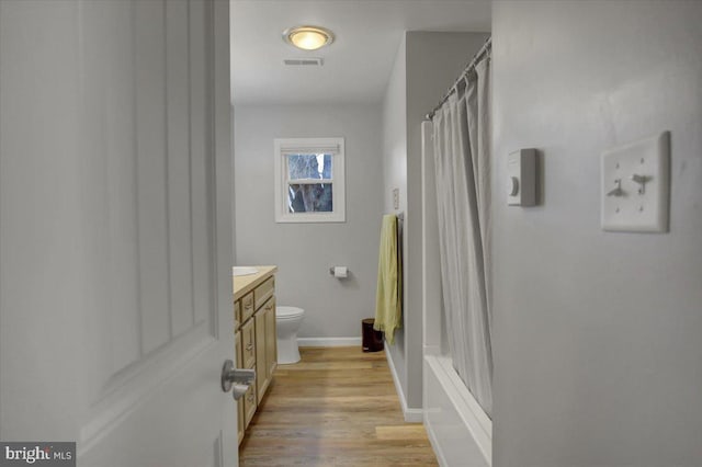 full bathroom featuring vanity, wood-type flooring, shower / bath combo with shower curtain, and toilet