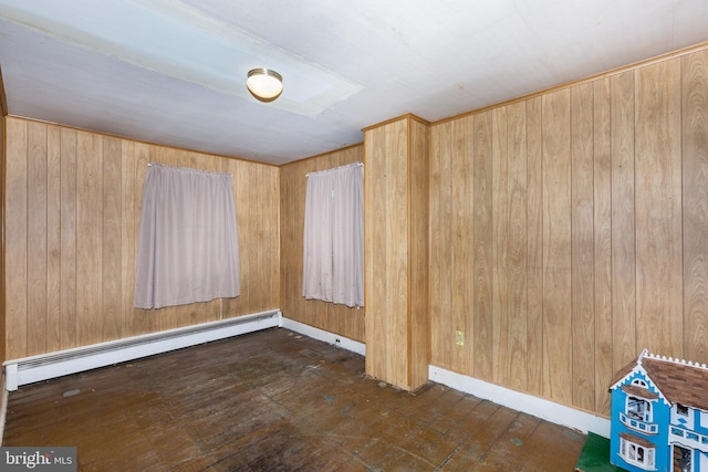 spare room featuring baseboard heating and wood walls