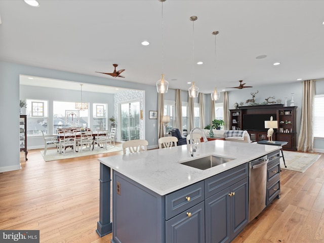 kitchen featuring ceiling fan with notable chandelier, hanging light fixtures, sink, and a kitchen island with sink