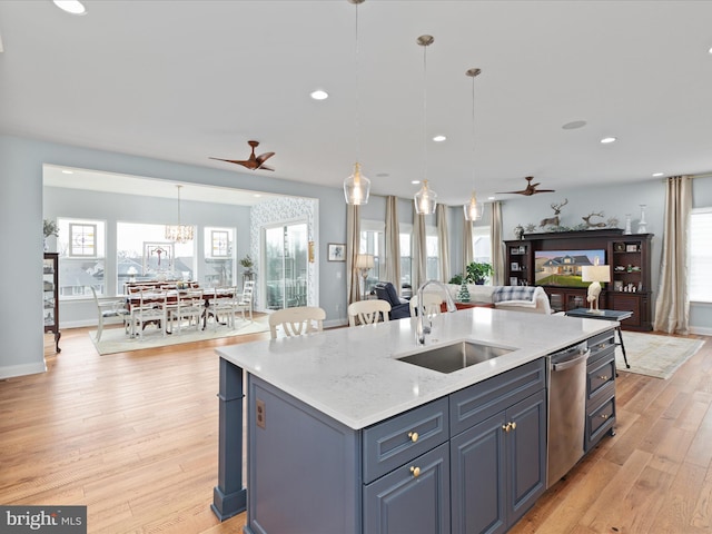 kitchen featuring pendant lighting, ceiling fan with notable chandelier, sink, and a kitchen island with sink