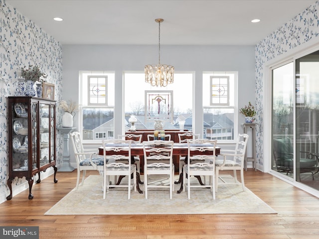 dining area featuring wood-type flooring, a wealth of natural light, and an inviting chandelier