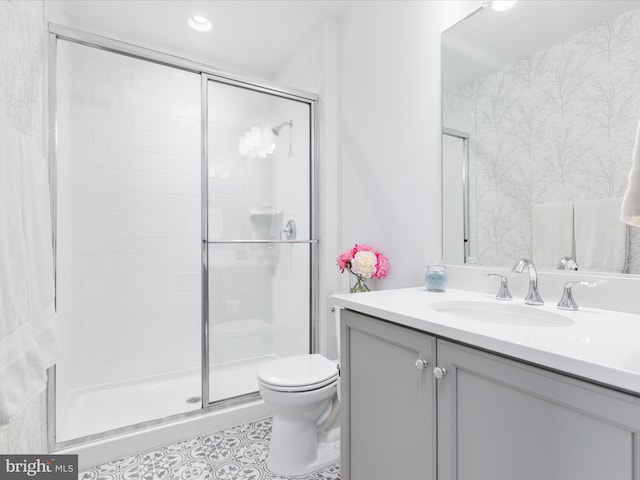 bathroom with vanity, toilet, and a shower with door