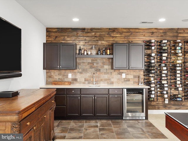 bar featuring dark brown cabinetry, sink, wine cooler, and tasteful backsplash