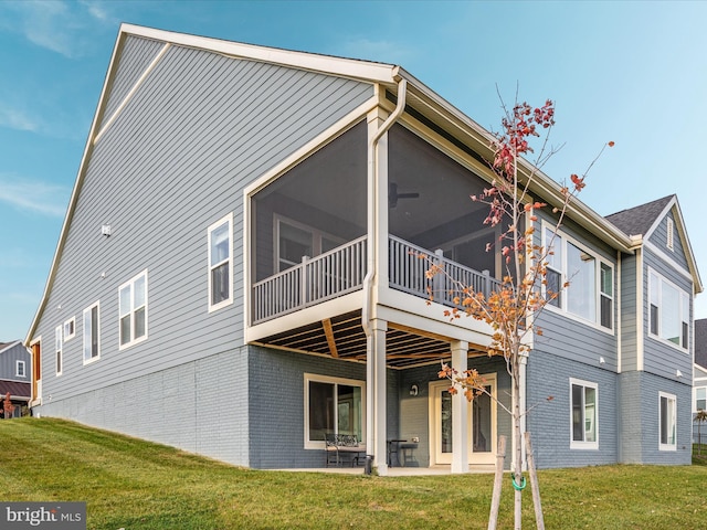 rear view of property featuring a sunroom, a patio area, and a lawn