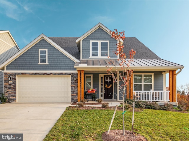 view of front of property featuring a porch, a garage, and a front yard